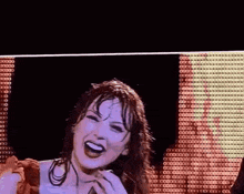 a woman is laughing on a stage with a microphone in her hand .