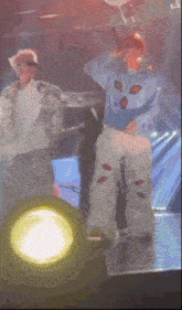 a man in a blue shirt with aliens on it is standing on a stage