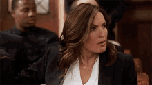 a woman in a suit is sitting in a court room
