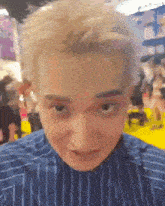 a man with blonde hair and a striped shirt is making a funny face
