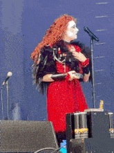 a woman with red hair is singing into a microphone on a stage