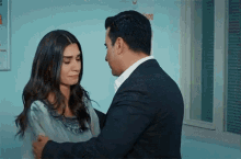 a man in a suit is hugging a woman in a room
