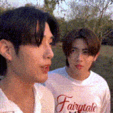 two young men are standing next to each other in a field .