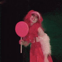a woman in a red dress holding a pink lollipop