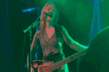 a person playing a guitar and singing into a microphone with a green light behind them