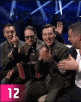 a group of men sitting next to each other with the number 12 on the bottom right