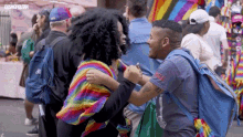 a woman in a rainbow sweater is hugging a man