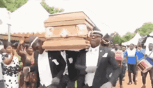 a group of men in tuxedos are carrying a coffin .