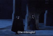 a man in a black cape stands next to a woman in a black dress and the words che imbroglio are on the screen