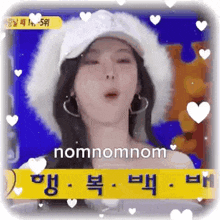 a woman wearing a hat and earrings is blowing a kiss on a screen .