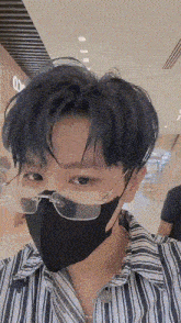 a young man wearing glasses and a mask looks at the camera