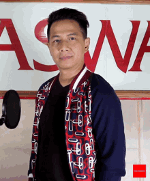 a man stands in front of a sign that says ' aswa ' on it