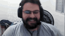 a man with a beard is wearing headphones and glasses and smiling .