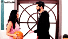 a woman in a pink dress is holding a basketball and a man in a black jacket is holding a basketball