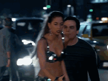a man and a woman walking down a street at night