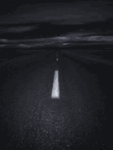a black and white photo of an empty road with a white line on it