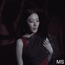a woman in a red dress stands in front of a red background with the letters ms on it