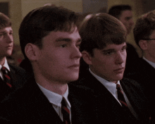 a group of men in suits and ties are sitting in a room