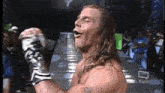 a man with long hair and a tattoo on his arm is standing in front of a crowd with his fist in the air