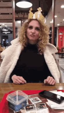 a woman wearing a crown sits at a table in a fast food restaurant