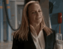 a woman in a black suit and white shirt is smiling