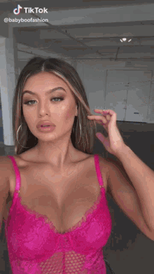a woman in a pink lace bra is taking a picture of herself