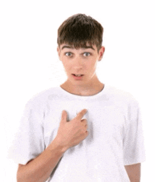 a young man in a white t-shirt is pointing at himself .