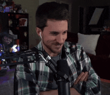 a man in a plaid shirt is sitting in front of a microphone