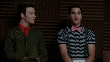 two men are sitting next to each other and one has a pink bow tie on