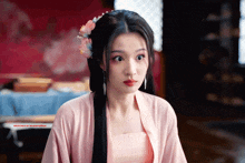 a woman wearing a pink top and a flower in her hair is looking at the camera
