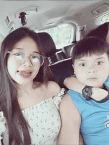 a girl wearing glasses is sitting next to a boy wearing a watch that says casio on it
