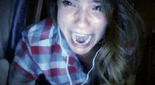a woman in a plaid shirt is crying while wearing headphones