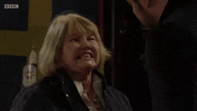 an elderly woman is laughing while standing next to a man .