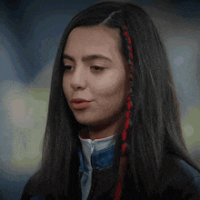 a woman with long black hair has red and black braids