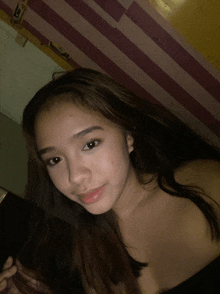 a woman taking a selfie with a pink and yellow striped wall in the background