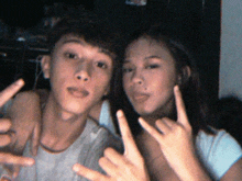 a boy and a girl are posing for a picture and the girl is giving a devil horns sign