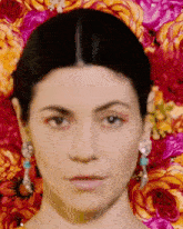 a close up of a woman 's face in front of a background of flowers