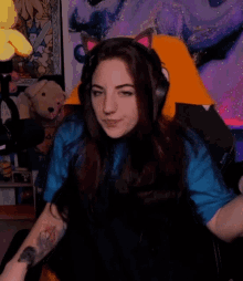 a woman wearing headphones and a cat ear pillow is sitting in a chair .