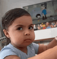 a little girl is making a funny face while sitting in front of a tv .