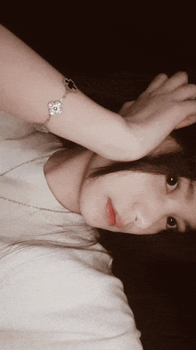 a woman wearing a bracelet covering her face with her hand