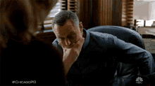 a man is sitting at a desk with his hand on his chin and #chicagopd written on the bottom right