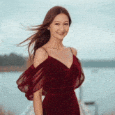 a woman in a red dress is standing in front of a lake
