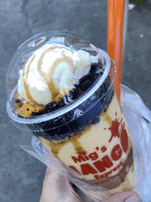 a person is holding a cup that says mig 's express on it