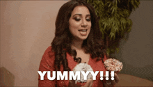 a woman in a red dress is holding a cupcake and says yummyy