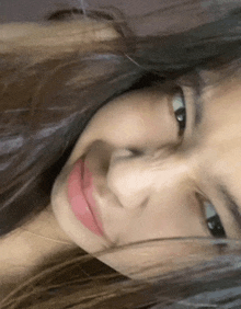 a close up of a woman 's face with her eyes closed and her hair blowing in the wind .