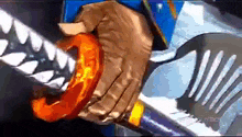 a close up of a person holding a sword with sharp teeth