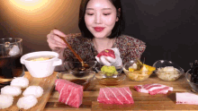 a woman is sitting at a table eating a variety of food with chopsticks