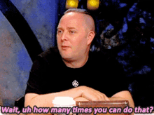 a man in a black shirt is sitting at a table and says wait uh how many times you can do that