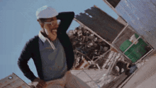 a man wearing a hard hat and glasses is standing in front of a pile of junk