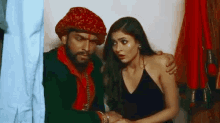 a man in a turban is standing next to a woman in a black dress .